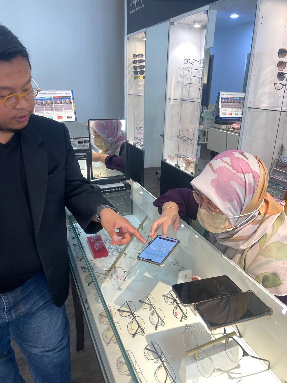 Optom DX being demonstrated on a phone over the counter of an optical shop