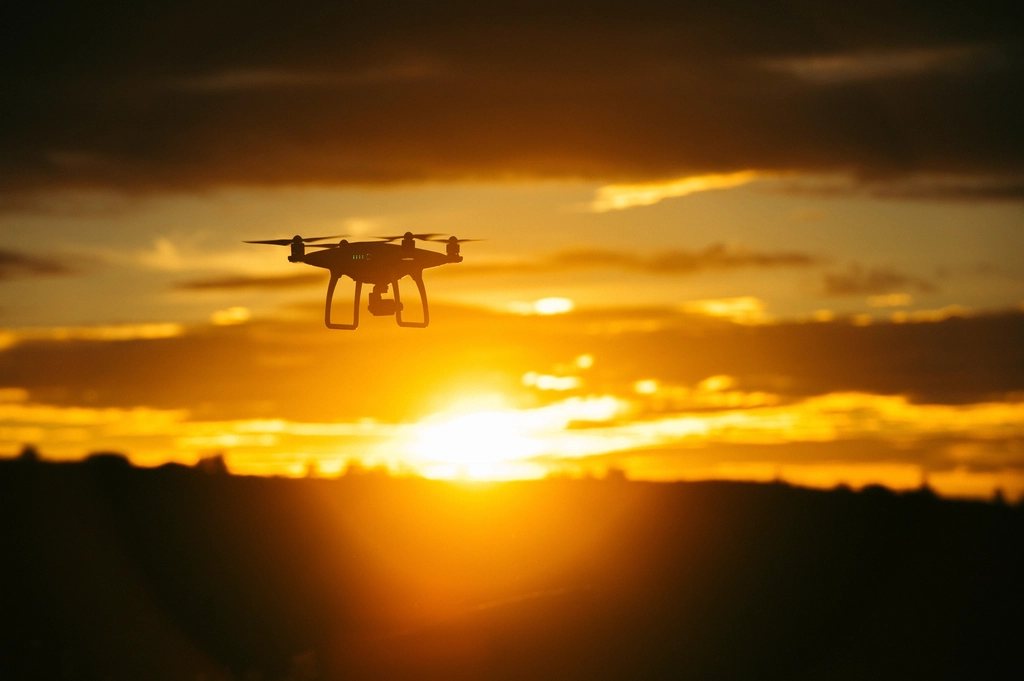 A drone in flight, silhouetted against a sunset