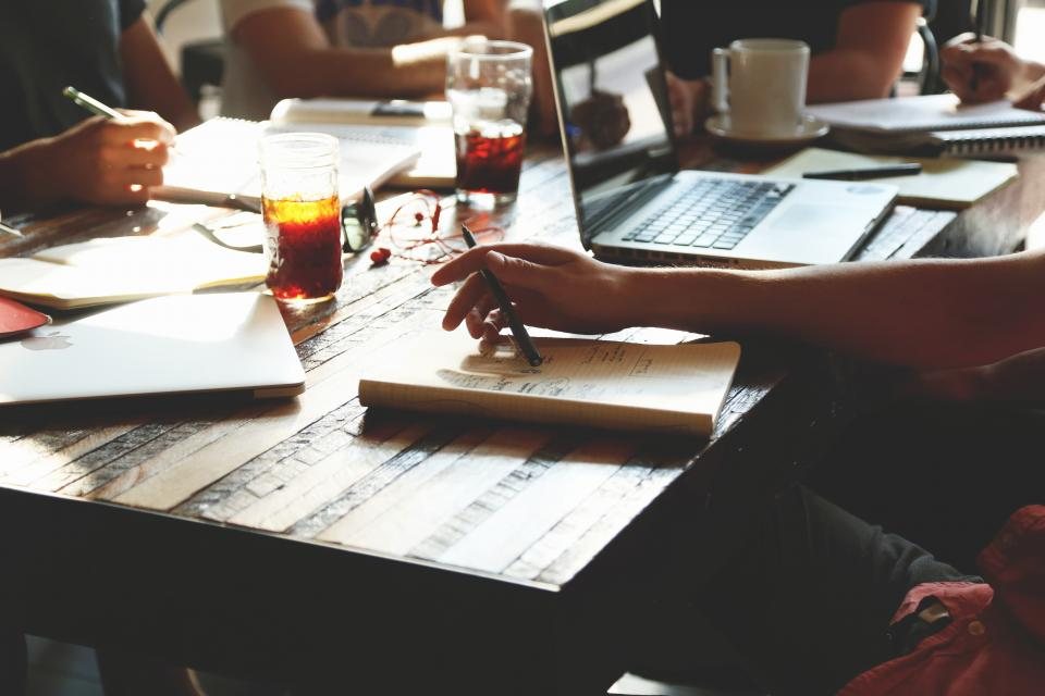 A team working around a table with notebooks and laptops